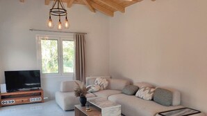Ein Wohnzimmer mit einem Ecksofa, einem Fernseher auf einem Holzboden, einem Marmortisch und einer Kronleuchter.