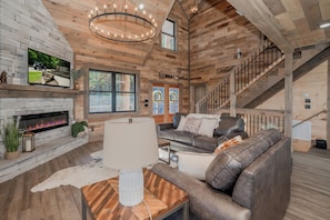 Un amplio salón con chimenea, sofá de cuero y una escalera.