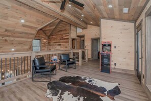 Een houten interieur met een hoge plafond, een vachttapijt en twee zwarte stoelen.