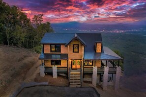 Une maison à deux étages dotée d’un balcon, située sur une colline et offrant une vue sur une vallée.