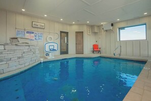 Une piscine intérieure dotée d’un poste de surveillance pour les sauveteurs, de panneaux indiquant les règles à respecter dans la piscine, et d’une fenêtre offrant une vue sur le ciel.