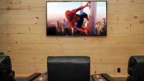 Una stanza con televisione montata su un muro in legno, sedute in pelle e vista sulla città.