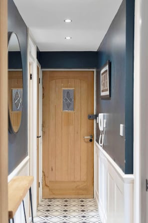 A hallway with a wooden door, a white telephone, and a mirror on the wall. - Edinburgh Stay | Near City Centre | Free Parking (Edinburgh)