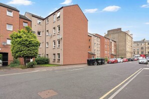 A residential street with multi-story buildings, parked cars, and a clear sky. - Edinburgh Stay | Near City Centre | Free Parking (Edinburgh)