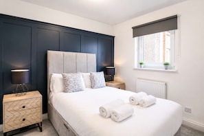 A bedroom with a bed, two bedside tables, a window with a view, and a radiator. - Edinburgh Stay | Near City Centre | Free Parking (Edinburgh)