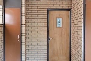 Une porte en bois avec une poignée en métal et une petite fenêtre ornée d’un motif décoratif.