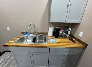 Eine Küchenzeile mit doppelter Spüle, Holz Arbeitsplatte und grauen Schränken.
