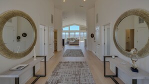 Un couloir avec deux grands miroirs, une console, un tapis et une vue sur l’espace de vie.