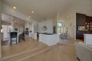 A spacious living area with a kitchen, dining area, and a large open space with a view.