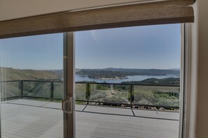 A balcony with a view of a lake and hills.