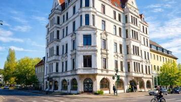 Un edificio a più piani con una torre imponente, finestre ad arco e un ingresso angolare.