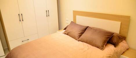 A bedroom with a bed, a nightstand, and a wardrobe.