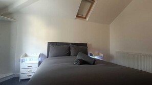 A bedroom with a bed, a nightstand, a dresser, and a window. - Hidden Gem with Hot Tub / Cinema + Secure Parking (Cardiff)