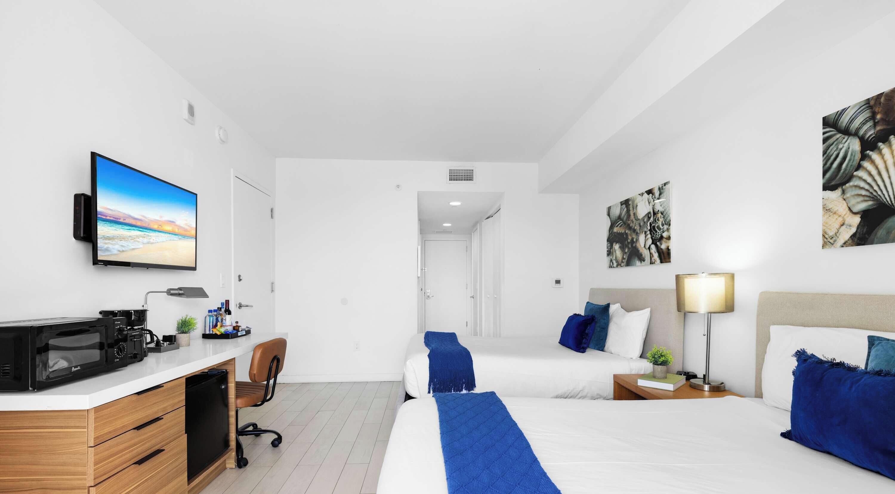 Een hotelkamer met een bed, nachtkastje, lamp en een bureau met een computer en printer.