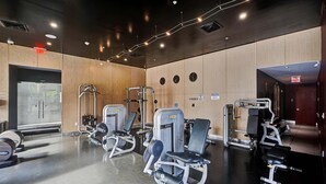 Ein Fitnessraum mit Trainingsgeräten, Holzwänden und einer Spiegelwand.