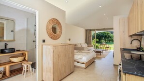 A modern room with a bed, a wooden cabinet, a sink, and a small dining area. - FIDEMAM (Anse Marcel)
