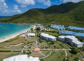 An aerial view of a resort with a beach, a central courtyard, and buildings with blue roofs. - FIDEMAM (Anse Marcel)