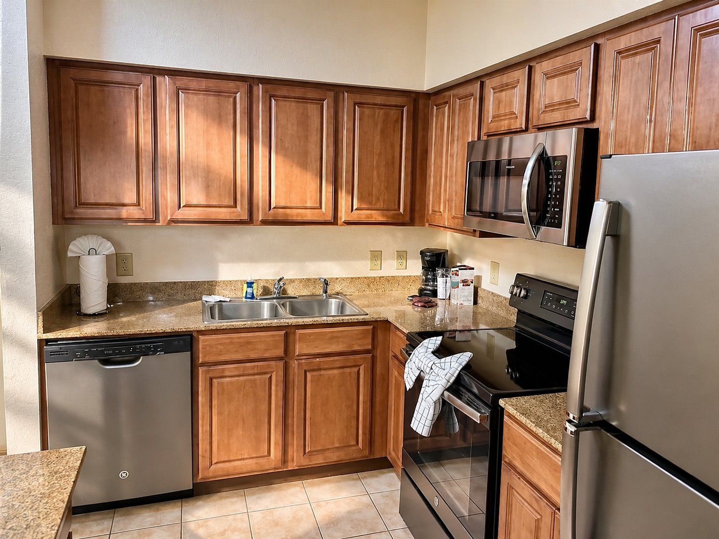 A kitchen with wooden cabinets, stainless steel appliances, a dishwasher, and a granite countertop.