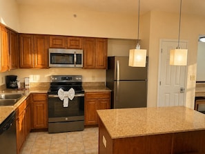 A kitchen with wooden cabinets, a stainless steel microwave, a refrigerator, a stove, and a sink. - 3BR Resort Suite on I-drive (Orlando)