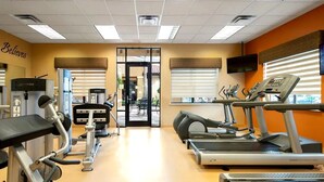 Un gimnasio con cintas de correr, elípticas y equipo de pesas.