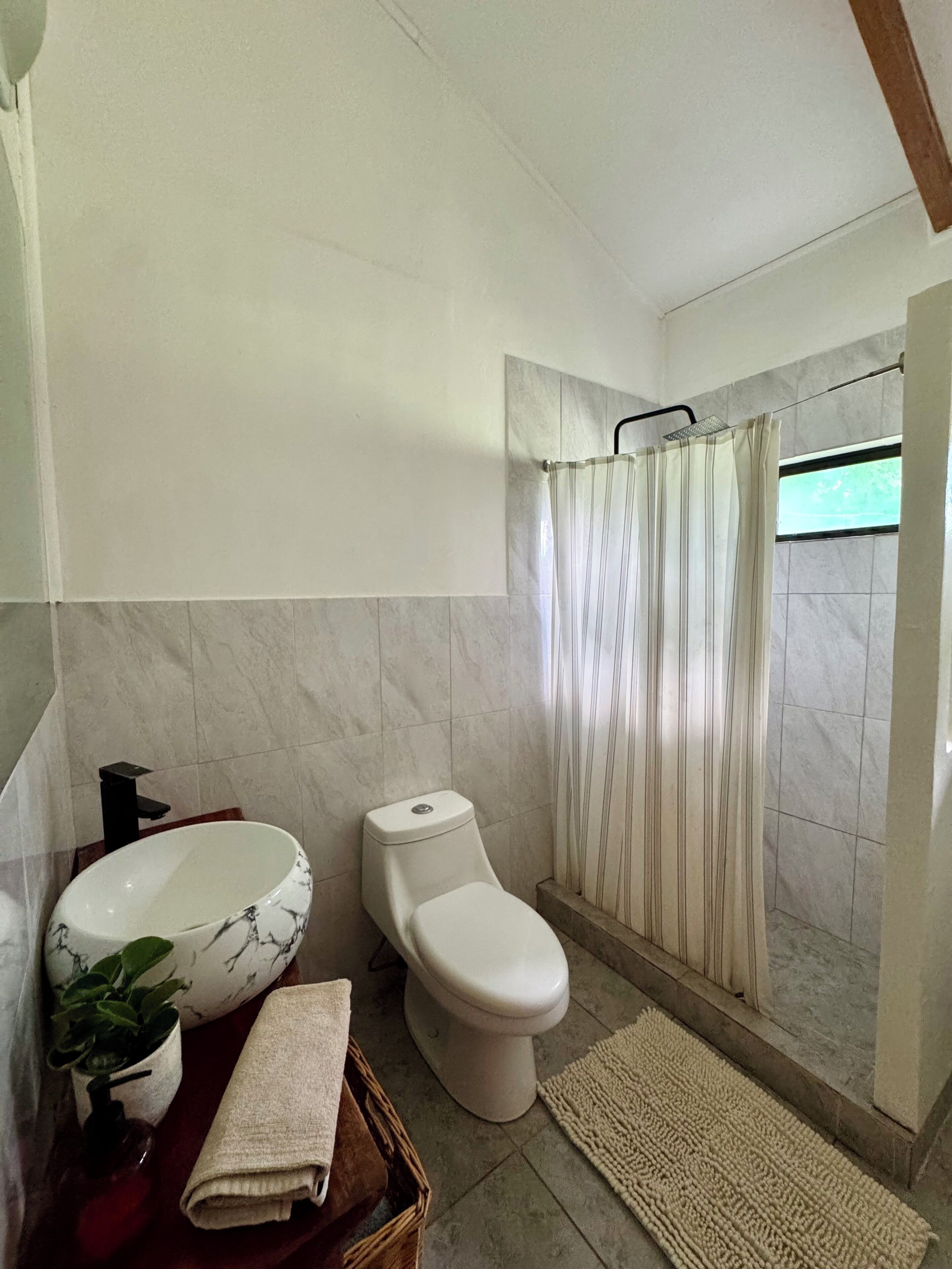 Un baño con lavamanos, inodoro y cortina de ducha de mármol.