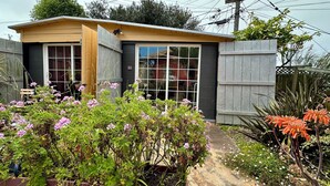 Een klein huis met een voortuin, een garage en een tuin vol planten en bloemen.