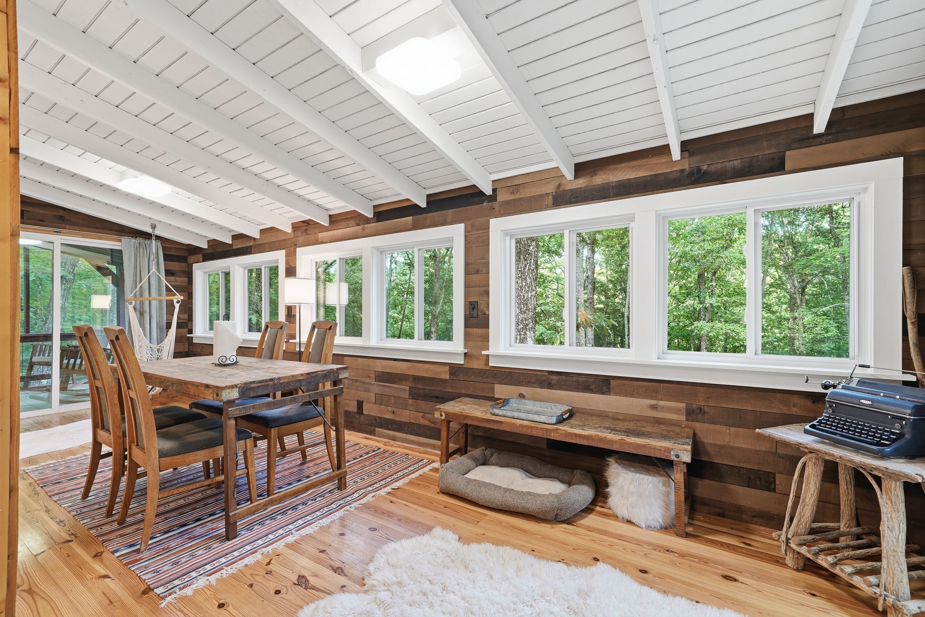 L’intérieur d’un chalet rustique comprend un coin repas, des murs en bois, de grandes fenêtres et une cheminée chaleureuse.