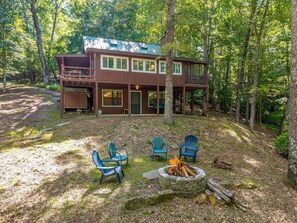 Eine Hütte mit Terrasse, Feuerstelle und Sitzgelegenheit im Freien.