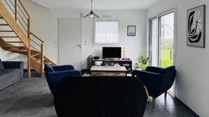 Een moderne woonkamer met een trap, een flatscreen televisie en een groot raam.