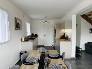 Eine moderne Küche mit Essbereich, einer Treppe und Blick ins Freie.