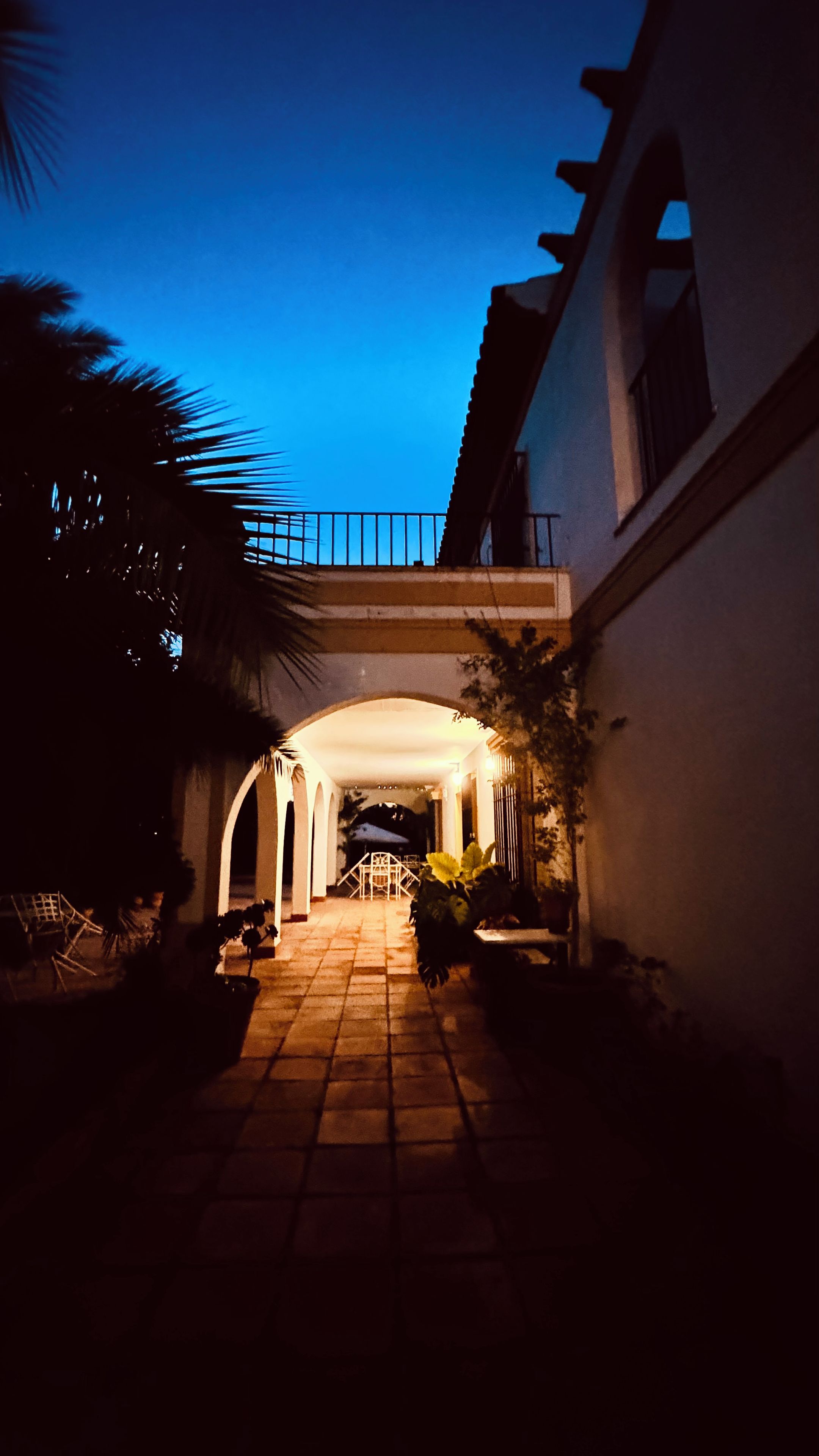 A pathway leading to a building with a covered entrance and a balcony.