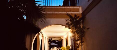 A pathway leading to a building with a covered entrance and a balcony.