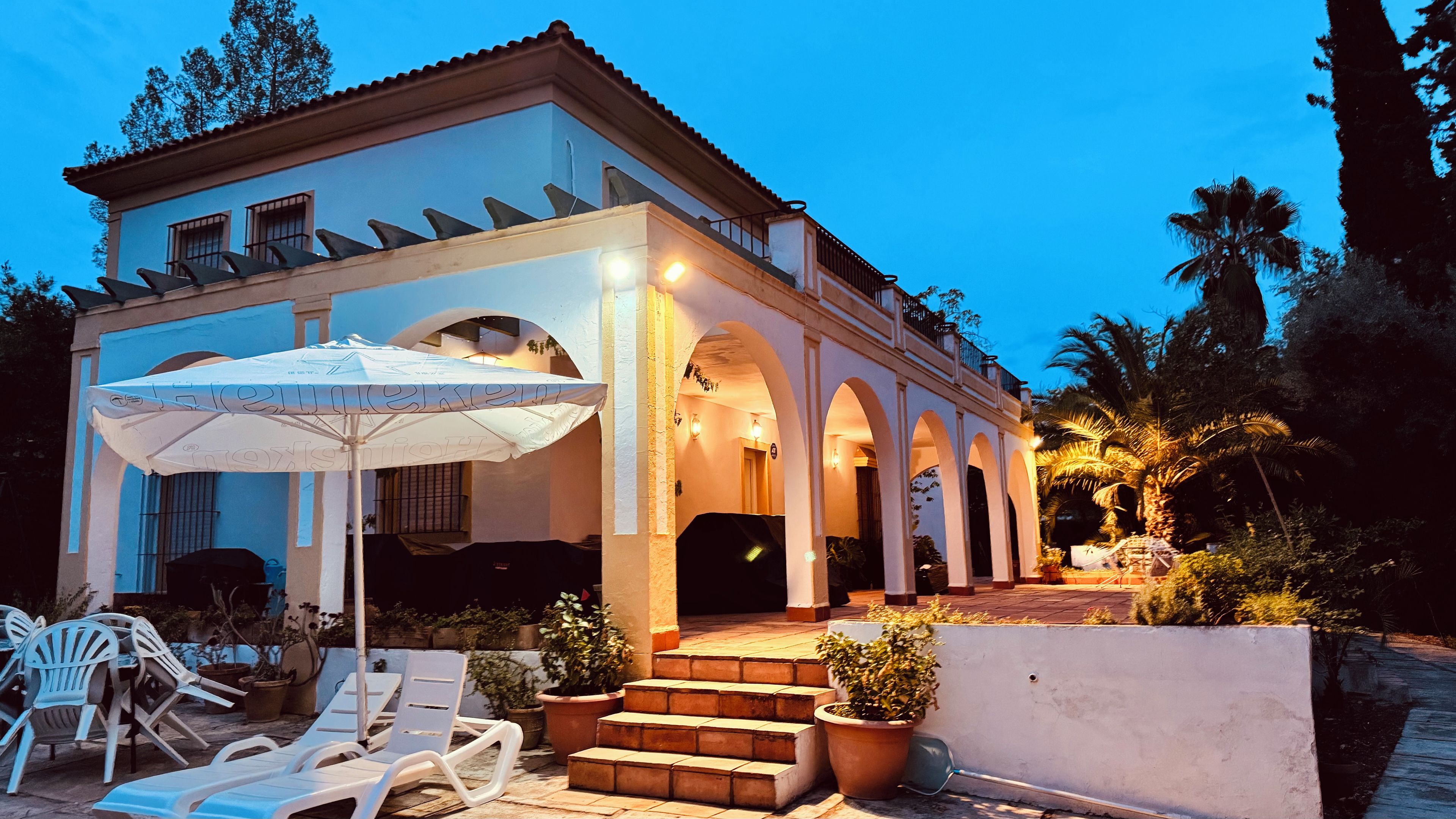 A building with a covered patio area, outdoor seating, and steps leading to an entrance.