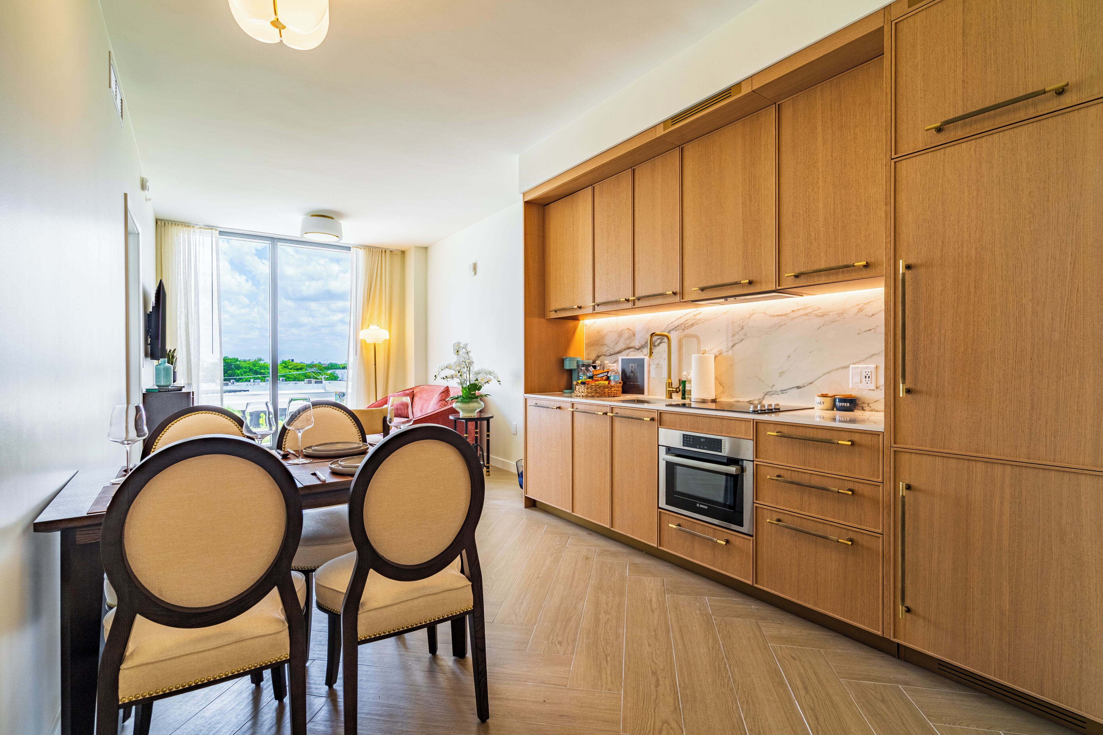Une cuisine moderne avec des meubles en bois, un coin repas avec des chaises et une grande fenêtre offrant une belle vue.