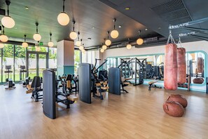 Ein Fitnessstudio mit Trainingsgeräten, Sandsäcken und großen Fenstern.