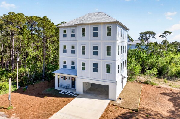 A multi-story building with a covered porch and a garage. - Golden Getaway — Luxury Coastal Home Near Beach (Santa Rosa Beach)