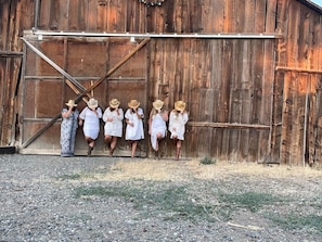 A rustic wooden barn with a metal door and a gravel ground.