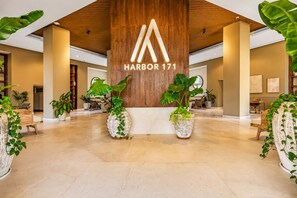A spacious lobby with a wooden ceiling and a large illuminated 'HARBOR 171' sign. - Oceanview - 1BR Condo at Harbor 171 | Beachfront, Rooftop Pool & Terrace (Puerto Vallarta)