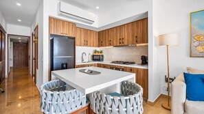Fully equipped kitchen with clean lines, white countertops, and warm wood cabinetry, perfect for cooking, entertaining, or casual meals. - Oceanview - 1BR Condo at Harbor 171 | Beachfront, Rooftop Pool & Terrace (Puerto Vallarta)