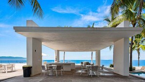 An outdoor seating area with tables and chairs, overlooking a body of water. - Ocean-view 1BR condo in Puerto Vallarta with pool, gym and balcony. (Puerto Vallarta)