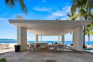 An outdoor seating area with tables and chairs, overlooking a body of water. - Ocean-view 1BR condo in Puerto Vallarta with pool, gym and balcony. (Puerto Vallarta)