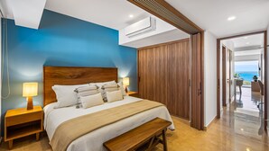 A modern bedroom with a large bed, wooden headboard, bedside lamps, and a view of the ocean. - Ocean-view 1BR condo in Puerto Vallarta with pool, gym and balcony. (Puerto Vallarta)