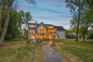 A two-story house with a covered porch, a stone pathway leading to the entrance, and a small tent set up in the yard.
