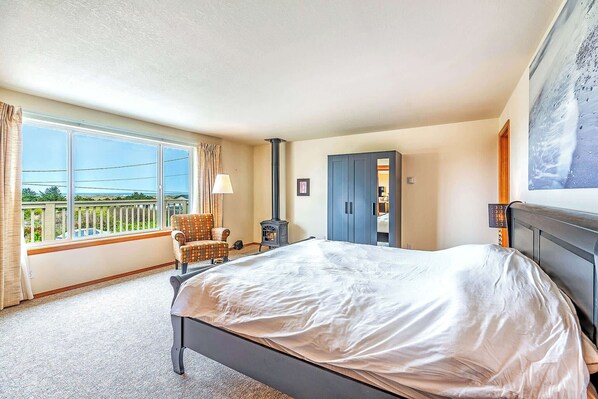 A bedroom with a bed, a chair, a wardrobe, a window with a view, and a fireplace.