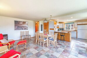 A modern kitchen with a dining area, wooden chairs, a table, and a view of the city.