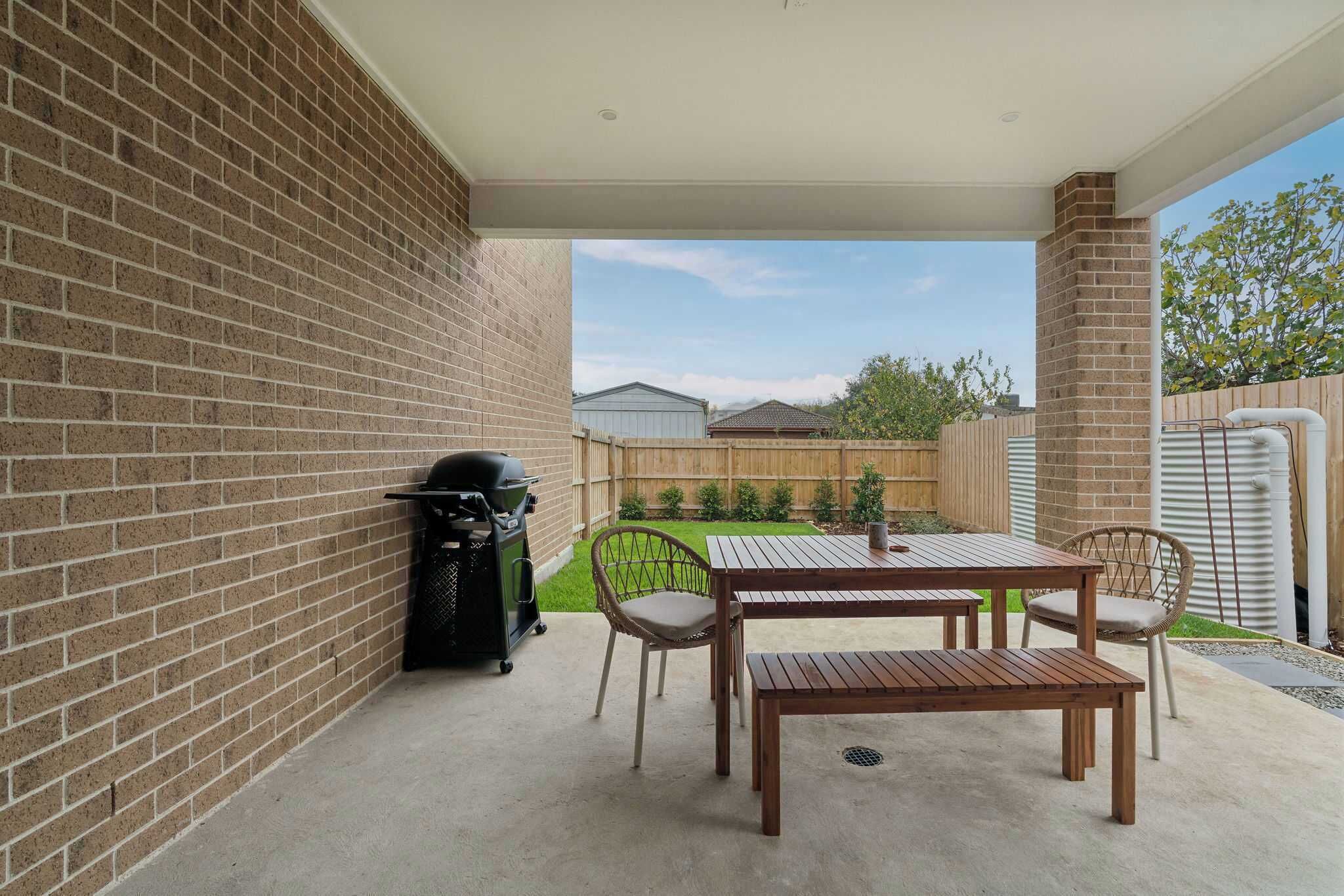 Eine Terrasse mit Backsteinmauer, Grill, Tisch und Stühlen.