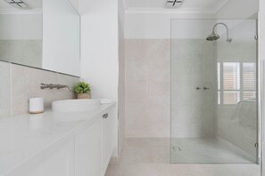 A modern bathroom with a glass-enclosed shower, a white sink, and a large mirror. - Beachurst Coastal Escape | Walk to Beach (Dromana)