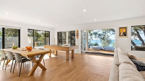 Uma sala de estar moderna com mesa de bilhar, espaço de jantar e grandes janelas com vista para o exterior.