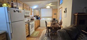 A compact kitchen with a refrigerator, microwave, stove, and wooden cabinets. - Clear Lake Retreat • Big Deck • Fire Pit • Views (Tionesta)