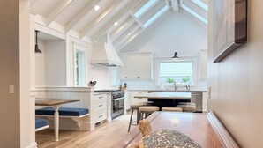 Une cuisine moderne avec des meubles blancs, une table à manger en bois et un élément décoratif original en forme de tortue.